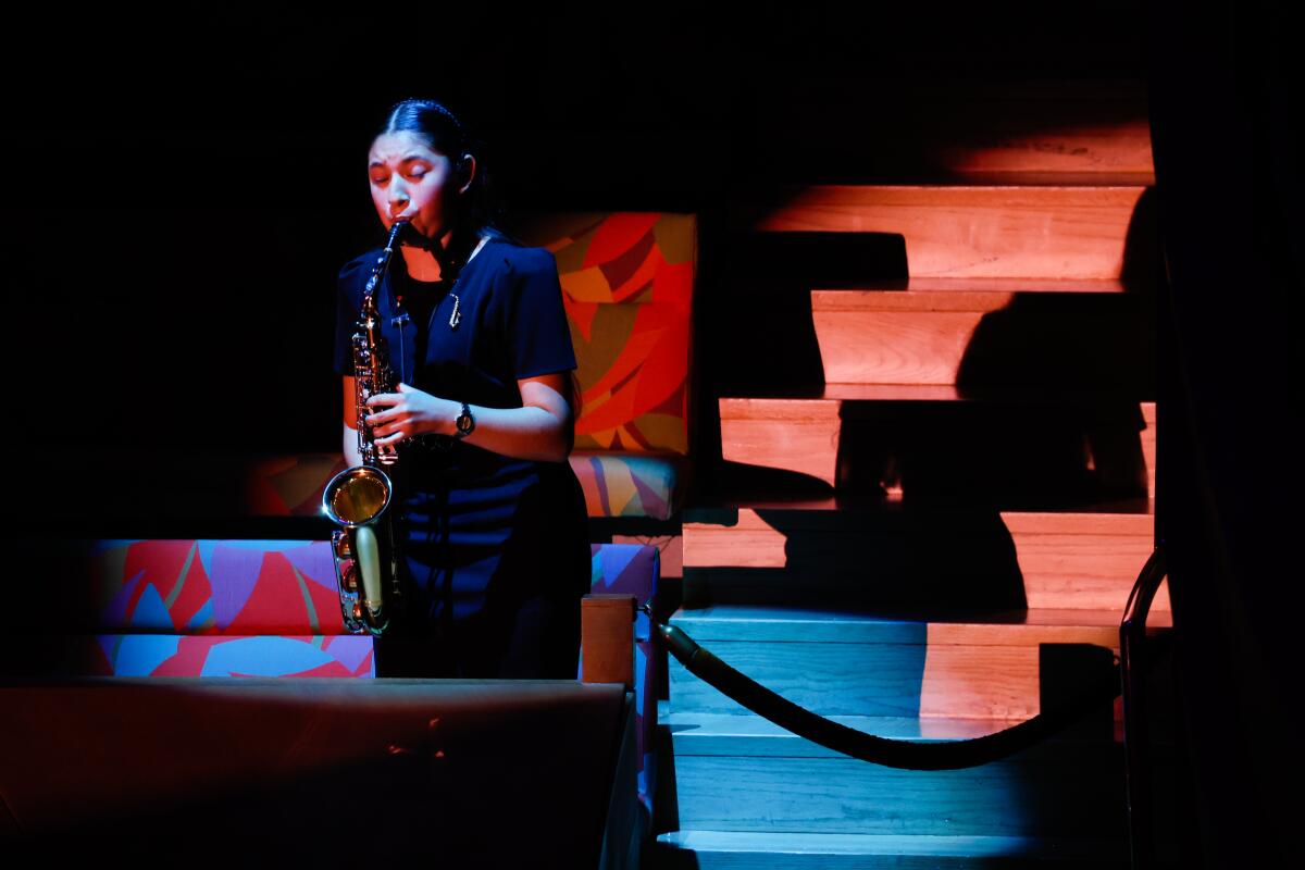 A student plays a saxophone on stage.