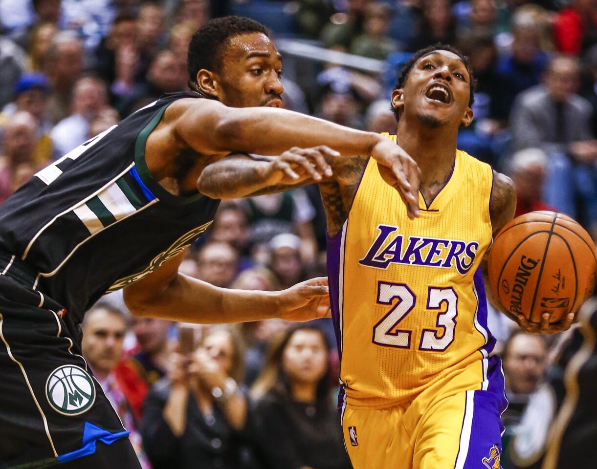 Lakers guard Louis Williams (23) is fouled by Bucks forward Jabari Parker as he drives to the basket in the first half.