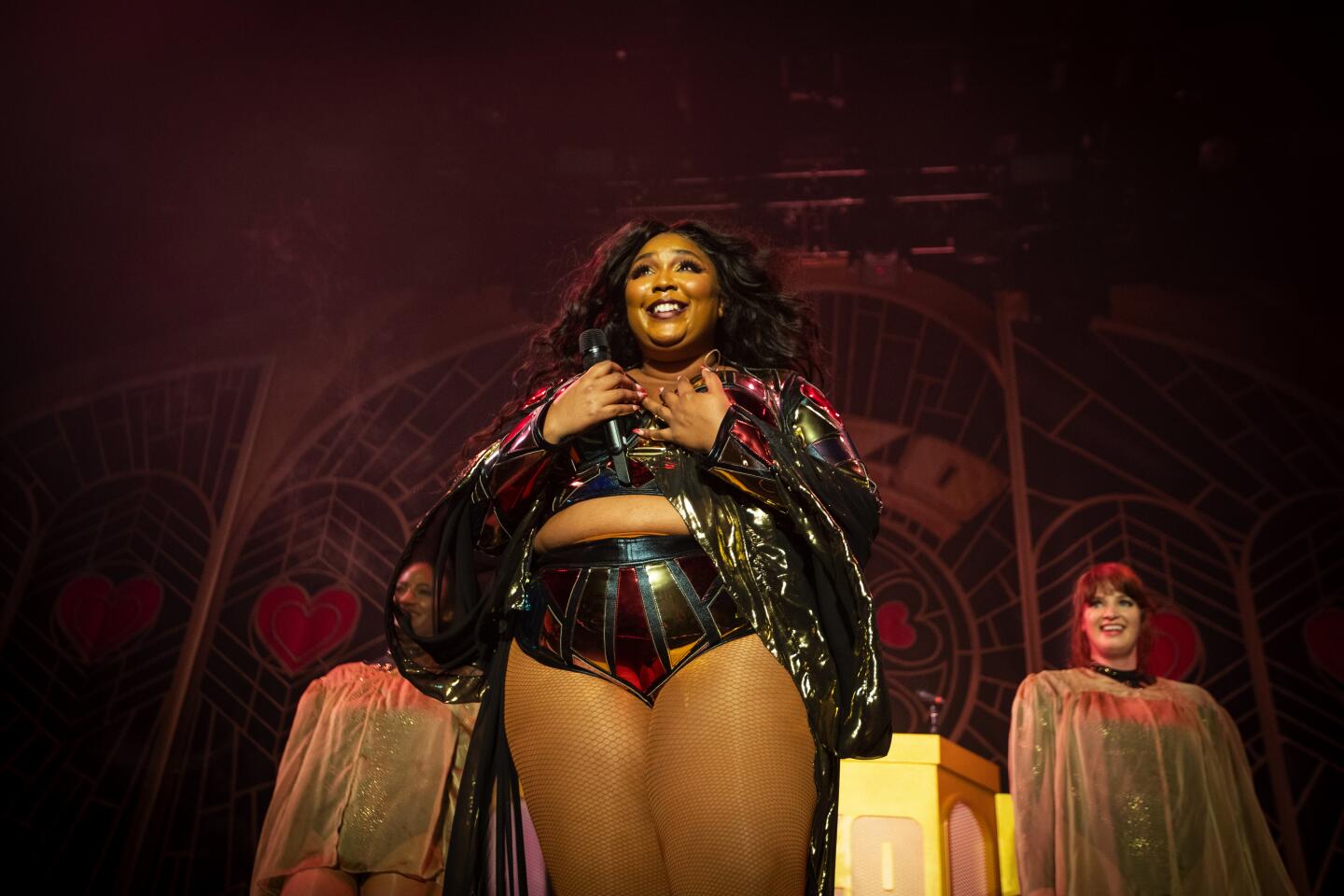 A woman onstage in black vinyl, looking happy