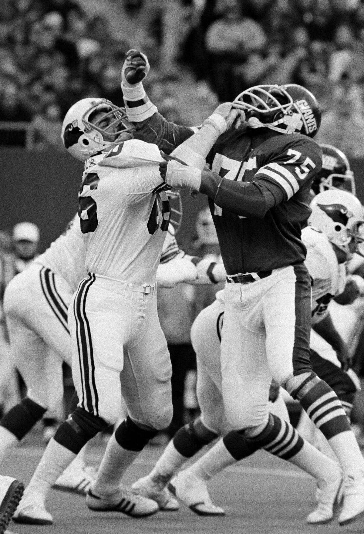 Conrad Dobler,left, of the St. Louis Cardinals, tries to block a charging George Martin of the New York Giants during the fourth period of the game at Giants Stadium, Dec. 5, 1977. Martin was trying to sack Jim Hart, the Cards' quarterback, and while Dobler stopped Martin, he received a 15¿yard penalty for "illegal use of the hands." (AP Photo/Ray Stubblebine)