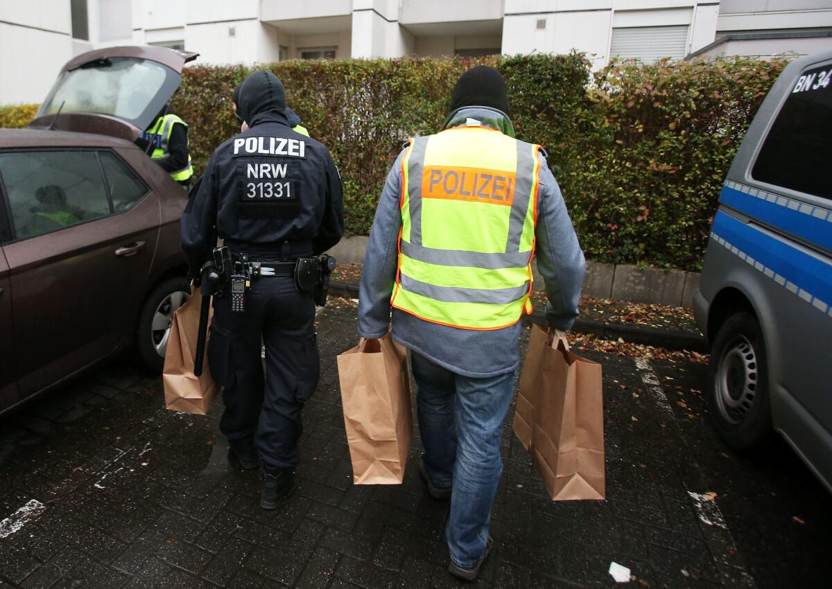 Police officers carry confiscated material to a car after raiding an apartment building in Bonn on Nov. 15.