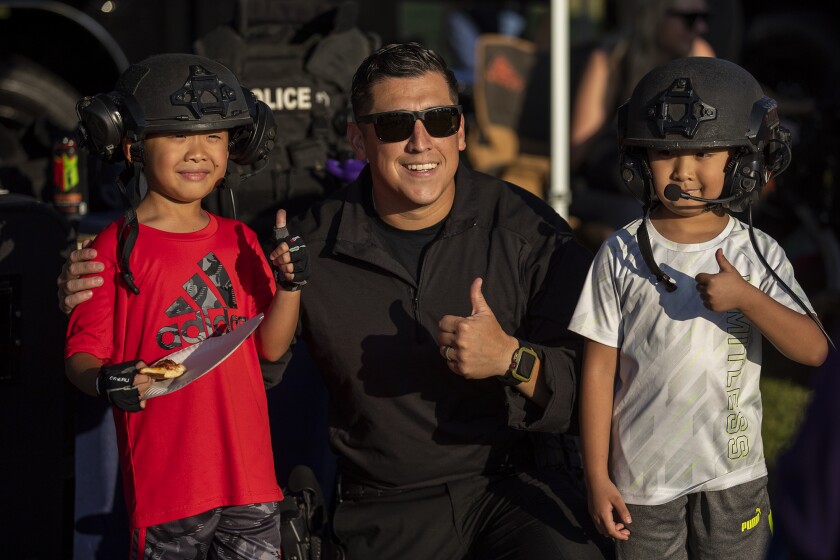 Fountain Valley Police Officer and West County SWAT team's George Diaz takes a photo with Isaac, 6, and Iszack Nguyen, 8.