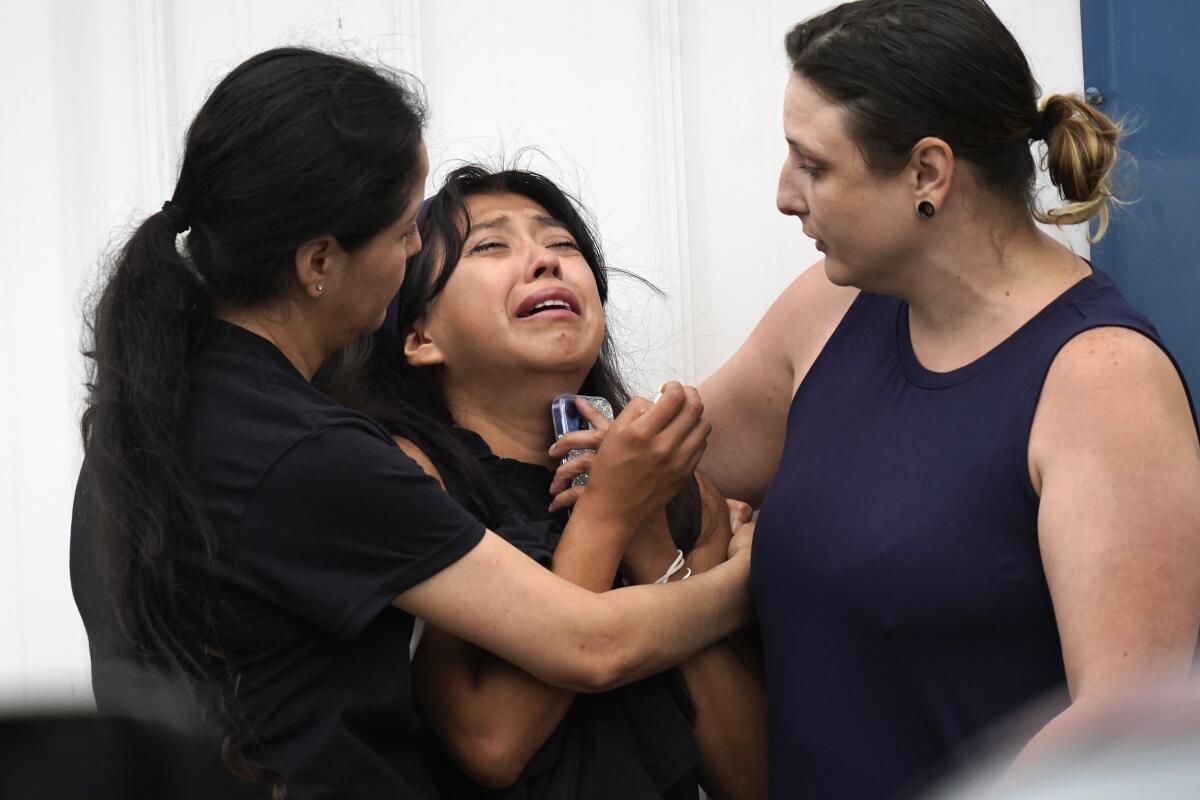 Yesenia Hernandez, center, granddaughter to Nicolas Toledo-Zaragoza, who was killed during a Fourth of July parade earlier in the week in Highland Park., Ill., is comforted outside the Iglesia Emanuel Church during a private family viewing before the funeral service, Friday, July 8, 2022, in Waukegan, Ill. (AP Photo/Charles Rex Arbogast)