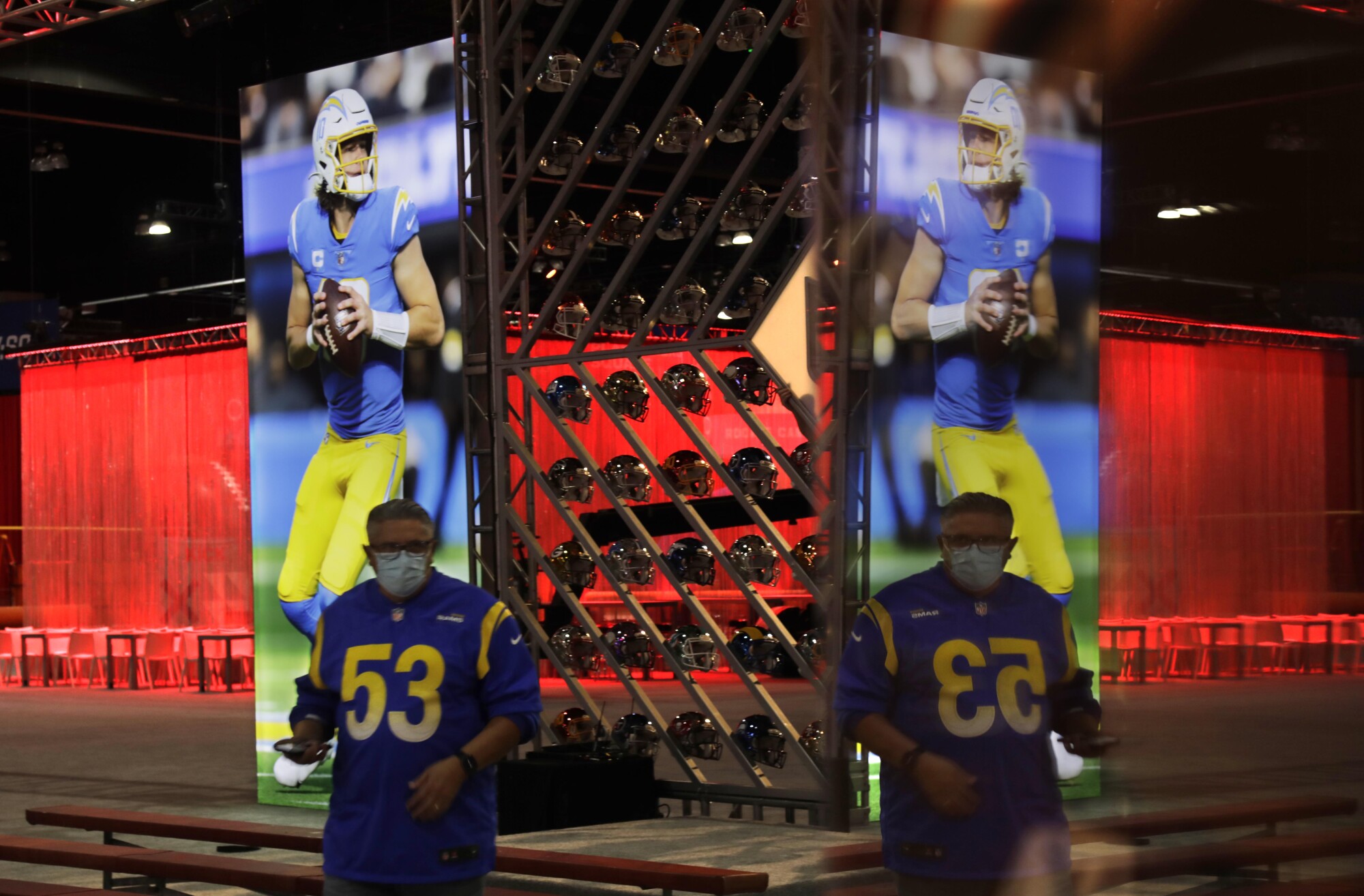 A man wearing a Rams jersey with the number 53 is reflected in a display 