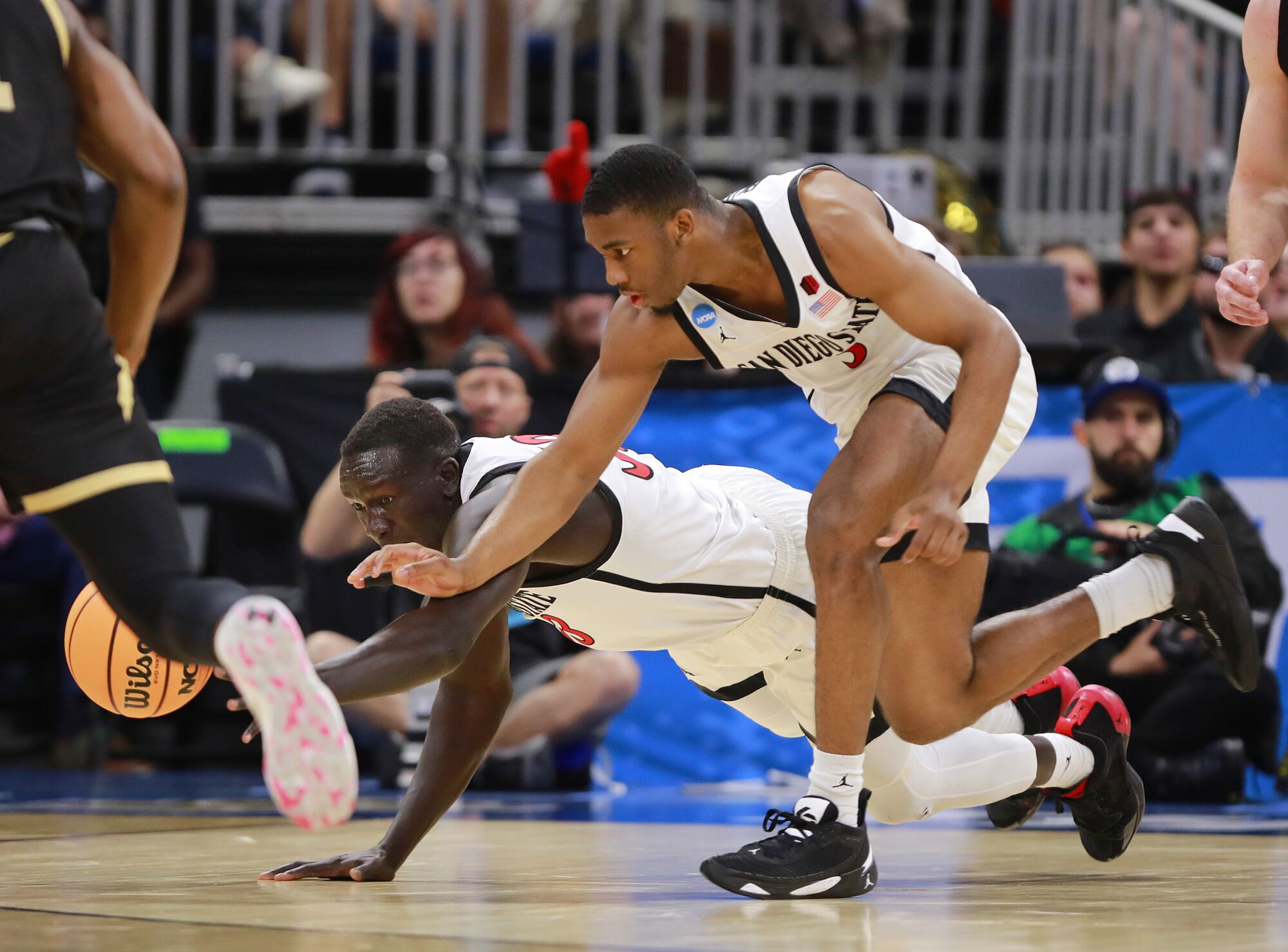 San Diego State's Aguek Arop, left, and Lamont Butler dive for a loose ball against the College of Charleston.