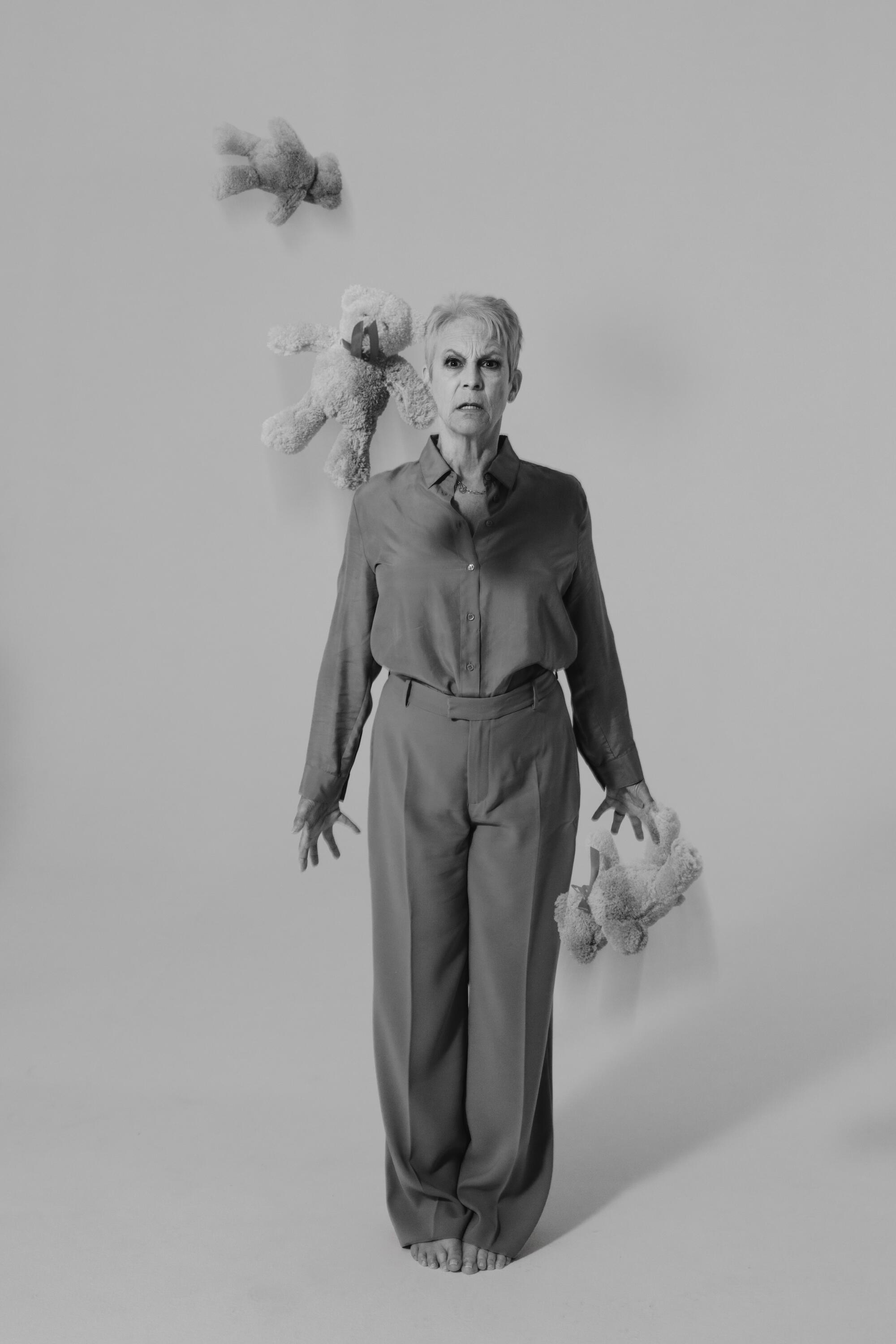 Jamie Lee Curtis tosses three stuffed bears and watches them fall for a portrait.