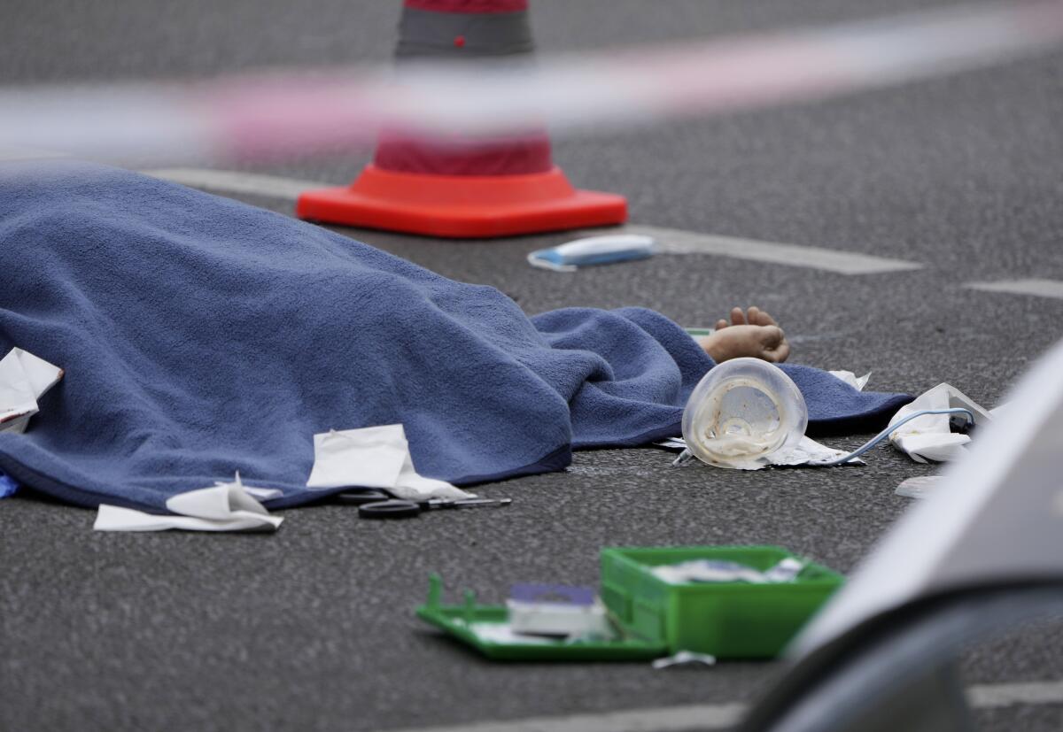 Un cadáver, cubierto con una manta, yace sobre el asfalto tras un atropello en el centro de Berlín, Alemania