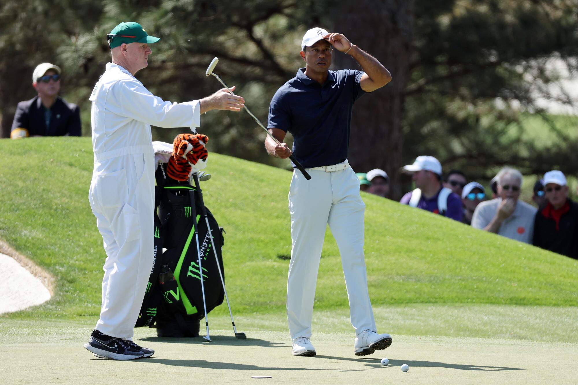 A caddie hands Tiger Woods a club