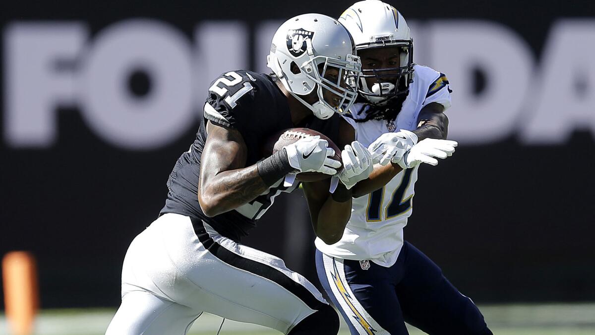Raiders cornerback Sean Smith (21) intercepts a pass intended for Chargers receiver Travis Benjamin during a game last season in Oakland.