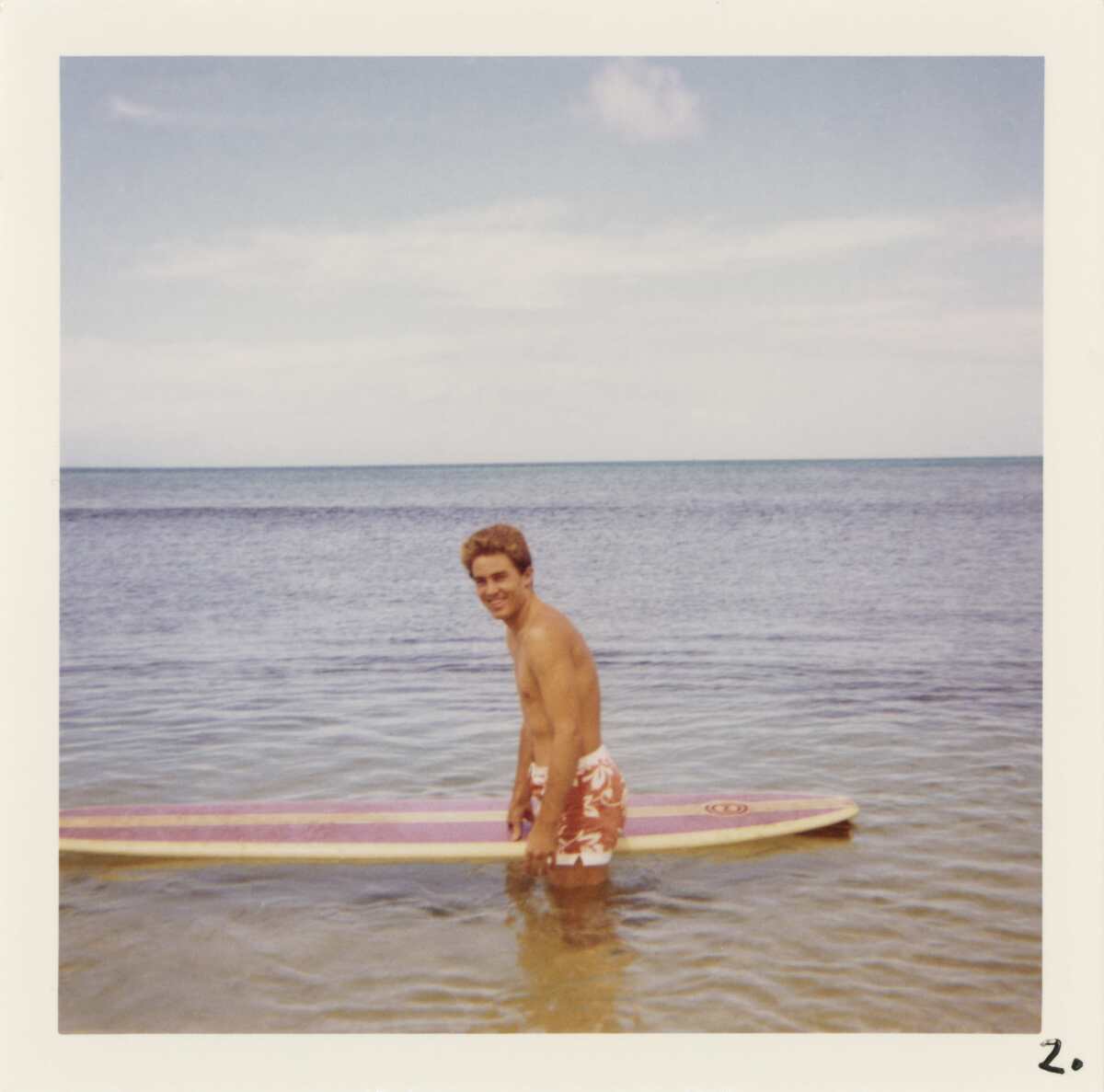 Jan Berry wades into water with a surfboard.