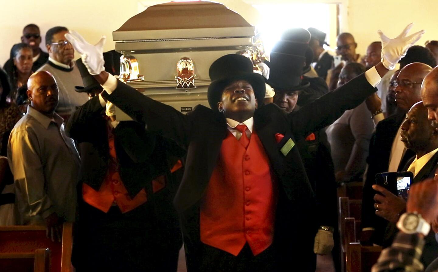 Professional pallbearer Marteze Gilmore leads his colleagues into the church as they bear the casket shoulder-high at a funeral service in South Los Angeles.