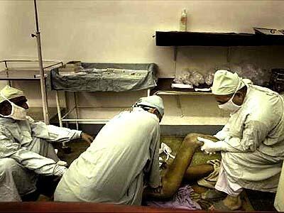 Surgeon Mohammed Ramzan, kneeling on floor at right, wrestles an Afghan patient's dislocated hip into place at Sandeman Civil Hospital in Quetta, Pakistan.