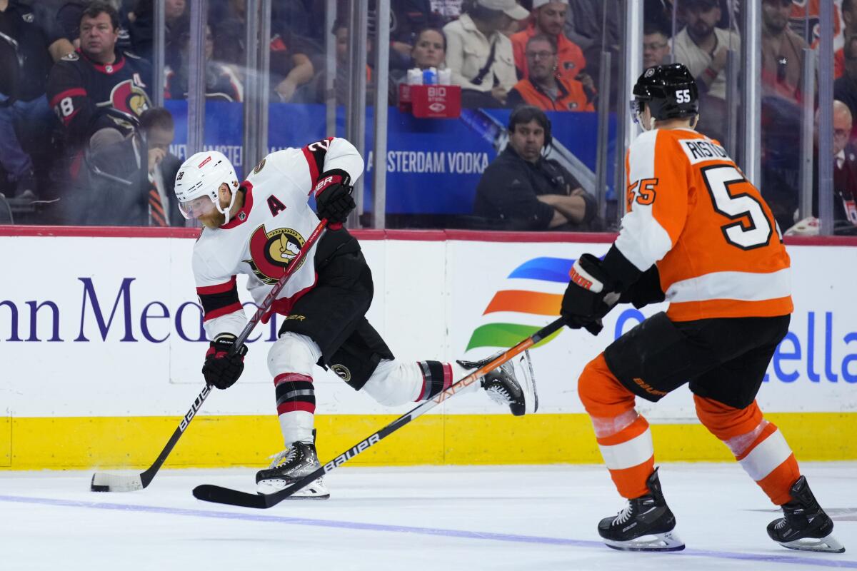Ottawa Senators' Claude Giroux, left, shoots the puck against Philadelphia Flyers' Rasmus Ristolainen during the third period of an NHL hockey game, Saturday, Nov. 12, 2022, in Philadelphia. (AP Photo/Matt Slocum)