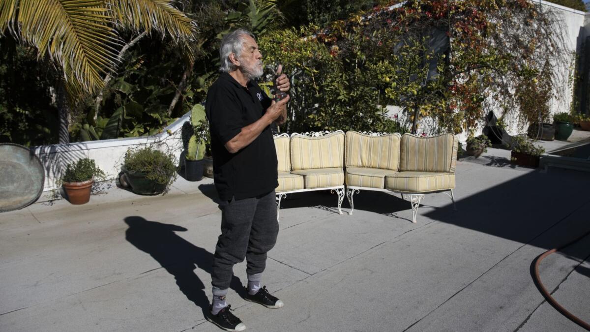 Comedian Tommy Chong smokes on the roof of his home in Pacific Palisades in 2017. He will be a featured guest on a cannabis tour with Green Tours starting this month.