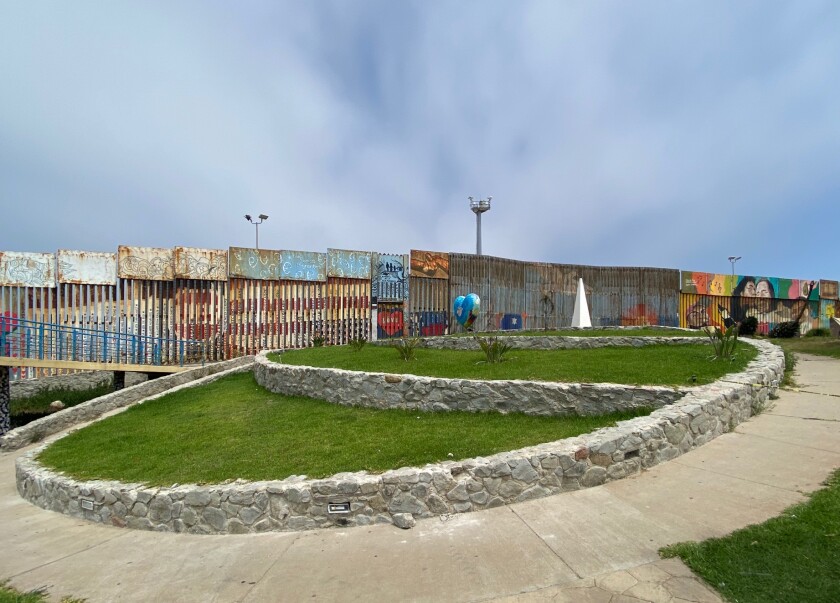 Walls with murals surround a city park with grassy tiered area.