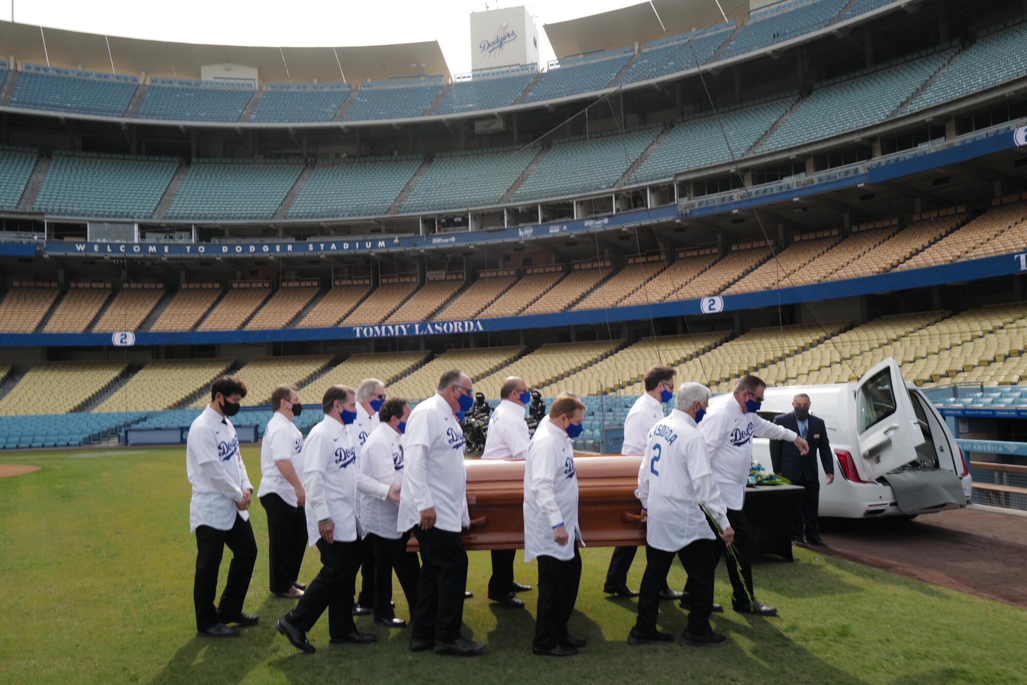 Pallbearers carry Tommy Lasaroda's casket at Dodger Stadium.