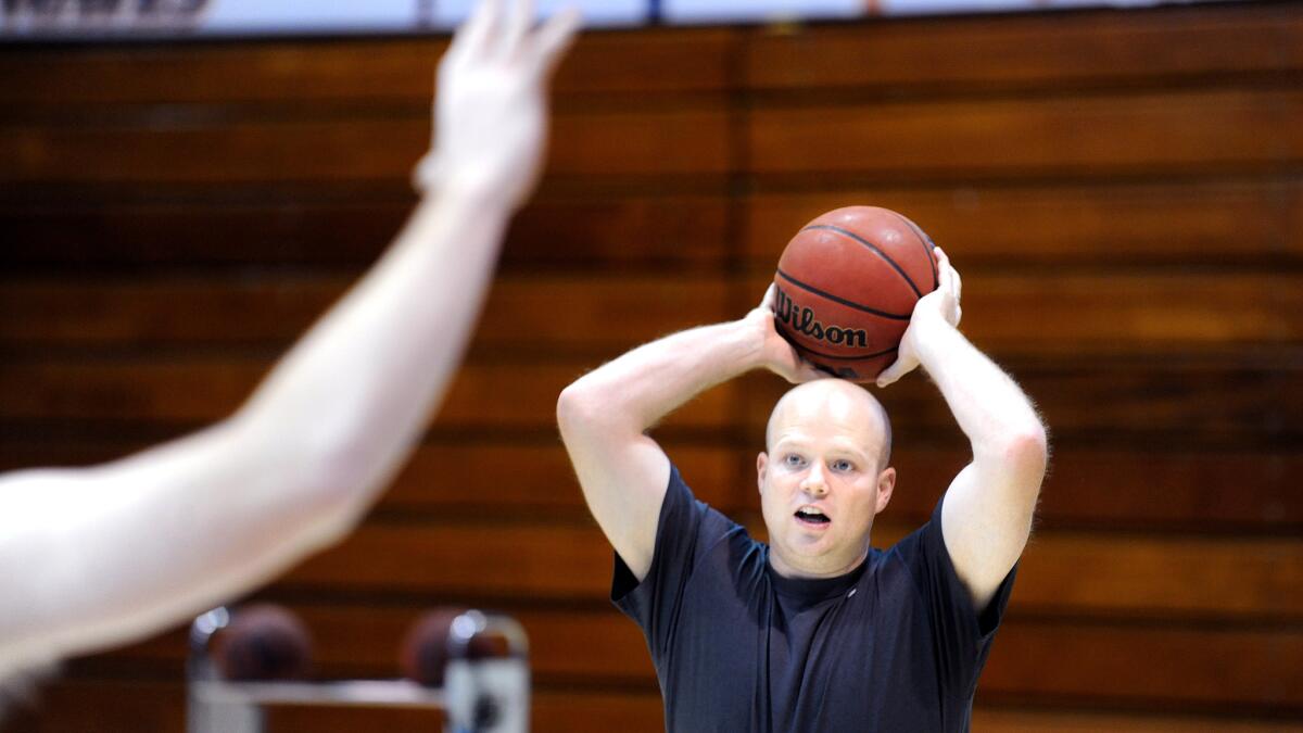 Pepperdine assistant coach John Impelman helps a player during a shooting drill.