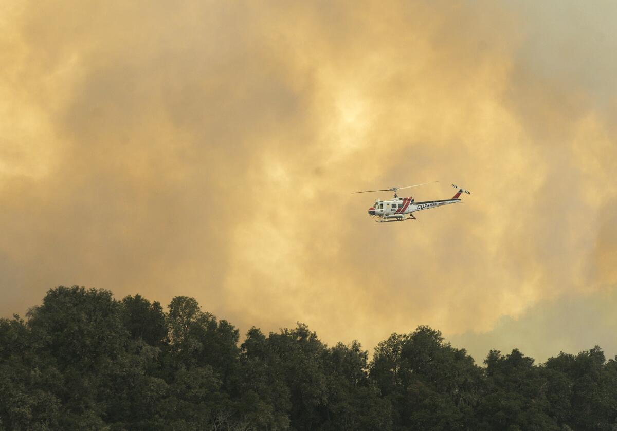 Un helicóptero de los bomberos se desplaza sobe un incendio forestal al suroeste de Cachagua, parte del esfuerzo para combatir el incendio Soberanes en el este del Valle de Carmel, en California, el lunes 1 de agosto de 2016. (David Royal/The Monterey County Herald vía AP) CREDITO OBLIGATORIO