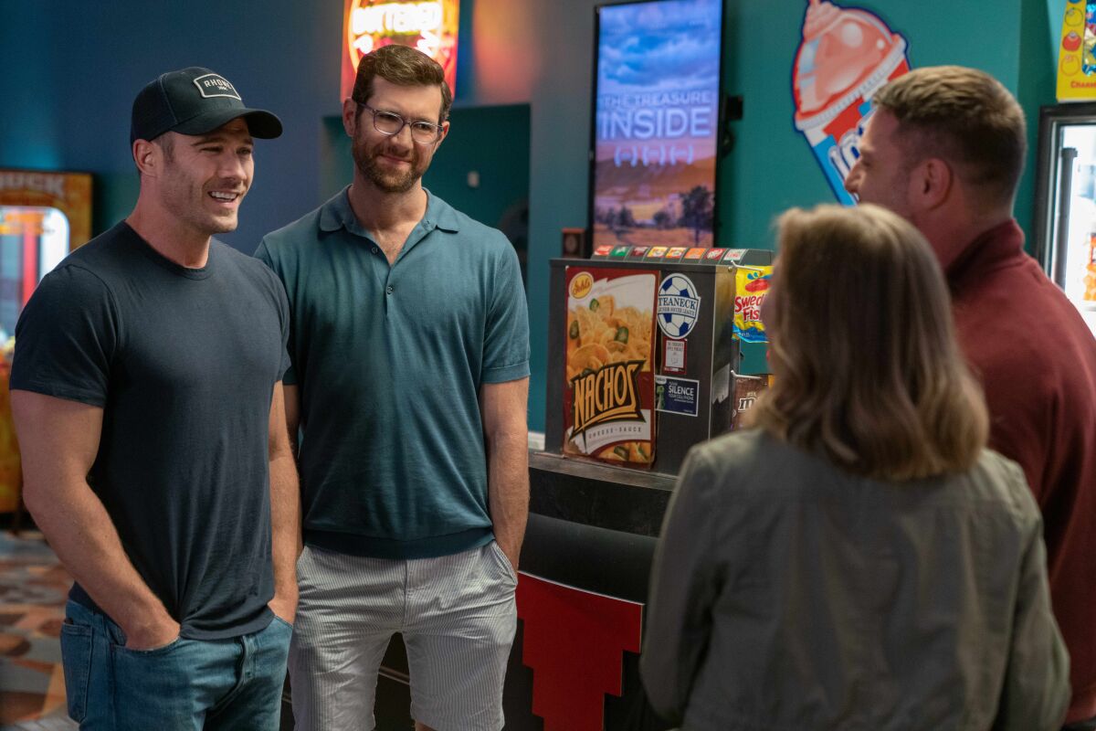 Two men chat with a woman and her male companion.