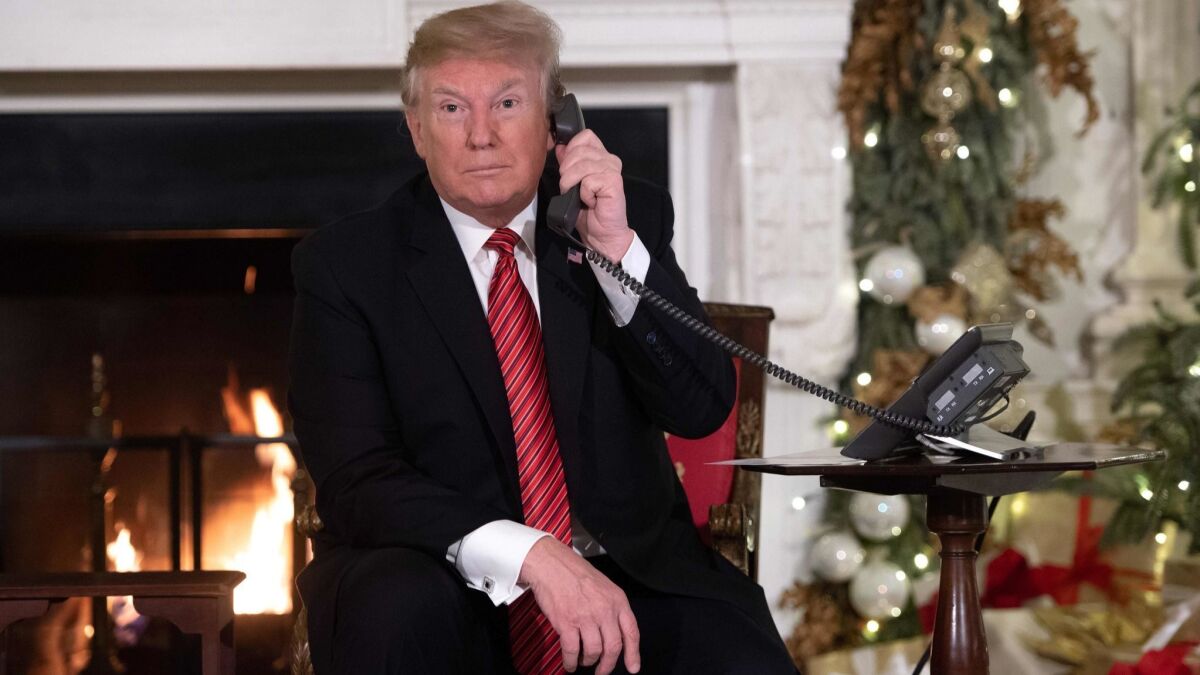 President Trump answers calls from people phoning the NORAD Tracks Santa program on Christmas Eve in the State Dining Room of the White House.