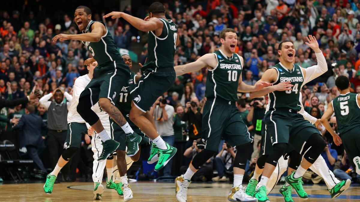 Alvin Ellis III, far left, and Marvin Clark, left, celebrate with their teammates after defeating Louisville, 76-70, in overtime at the NCAA tournament East Regional final in Syracuse, N.Y., on Sunday.