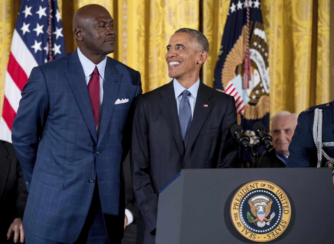 President Barack Obama, center, reacts as former NBA basketball player Michael Jordan, left, playfully looms over him at a Presidential Medal of Freedom ceremony in the East Room of the White House, Tuesday, Nov. 22, 2016, in Washington.