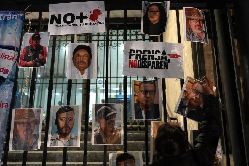 FILLE - A woman posts photos of murdered journalists during a national protest against the murder of journalists Lourdes Maldonado and freelance photojournalist Margarito Martínez in Mexico City, Jan. 25, 2022. (AP Photo/Eduardo Verdugo, File)
