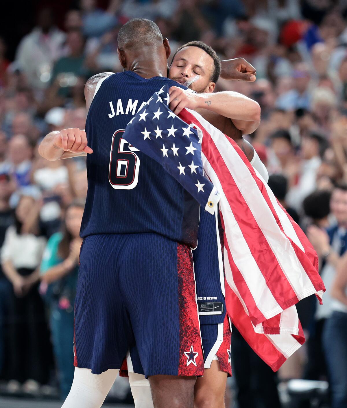 LeBron James embraces Stephen Curry, carrying an American flag 