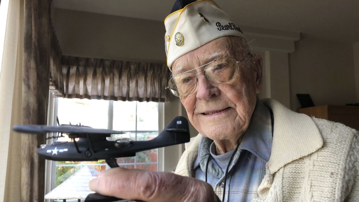 Retired U.S. Navy Cmdr. Don Long, at his Napa, Calif., home, holds a replica of the military seaplane he was in when Japanese warplanes attacked Hawaii 77 years ago.