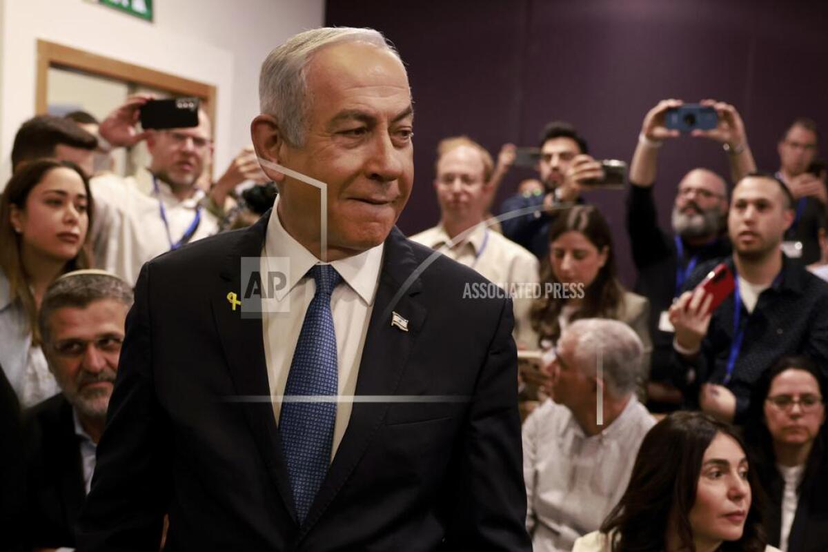 Israeli Prime Minister Benjamin Netanyahu arrives at court as people behind him take photos. 