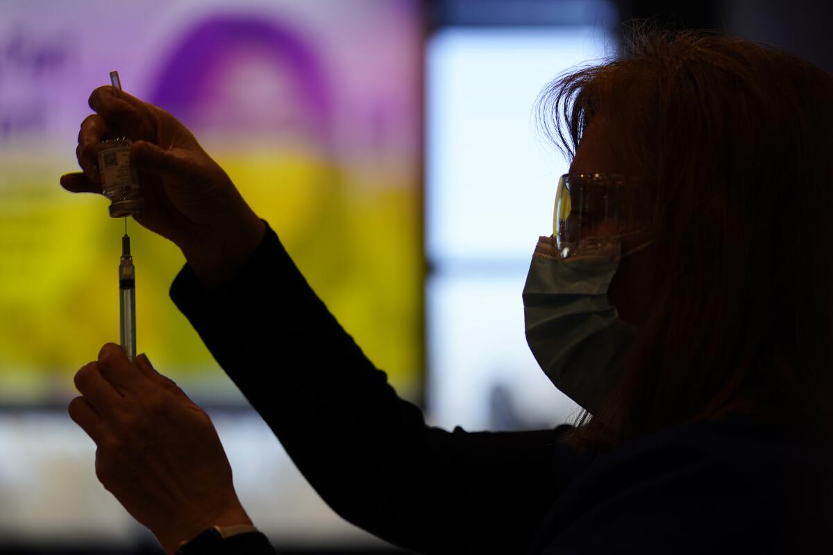 A woman fills a syringe with the COVID-19 vaccine made by Moderna. 