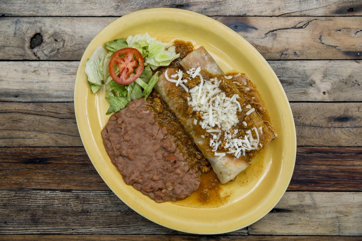 Two burritos de birria covered with salsa, green chile pork sauce and cheese