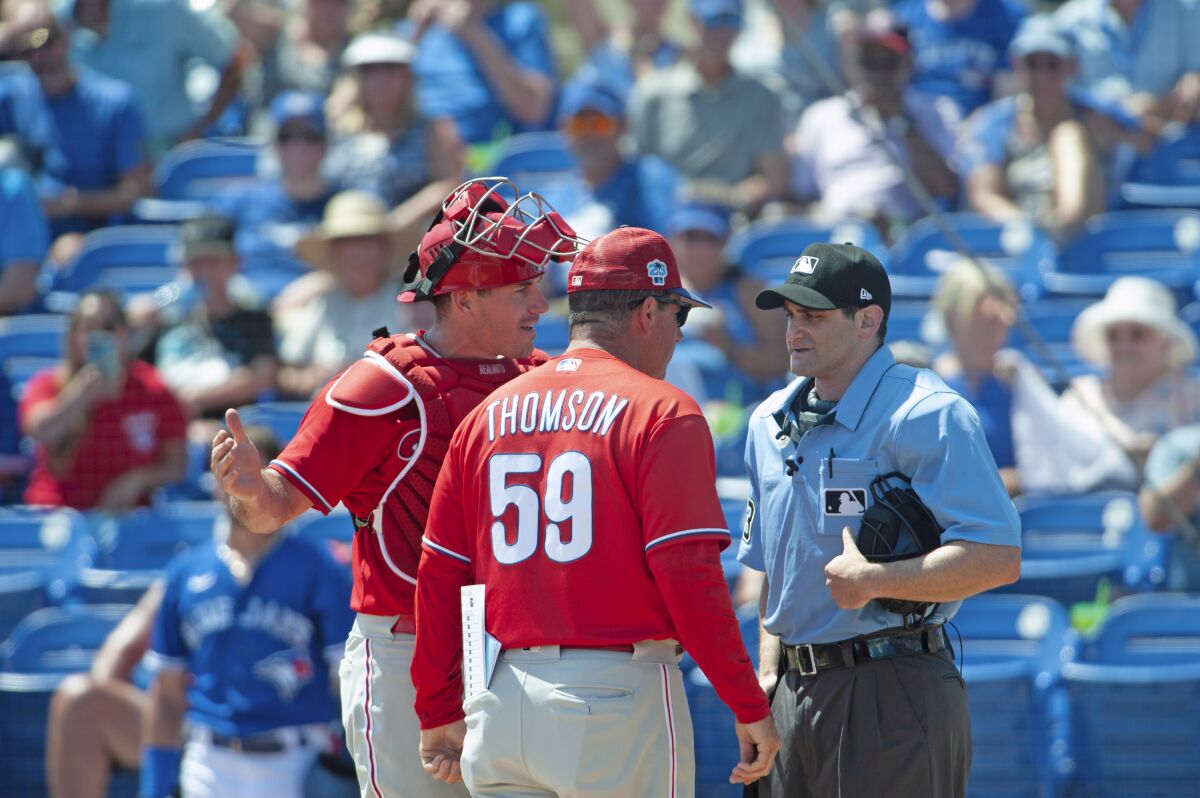 Philadelphia Phillies catcher J.T. Realmuto and manager Rob Thomson argue with umpire Randy Rosenberg after Realmuto was ejected from a spring training baseball game in Dunedin, Fla., Monday, March 27, 2023. (Mark Taylor/The Canadian Press via AP)