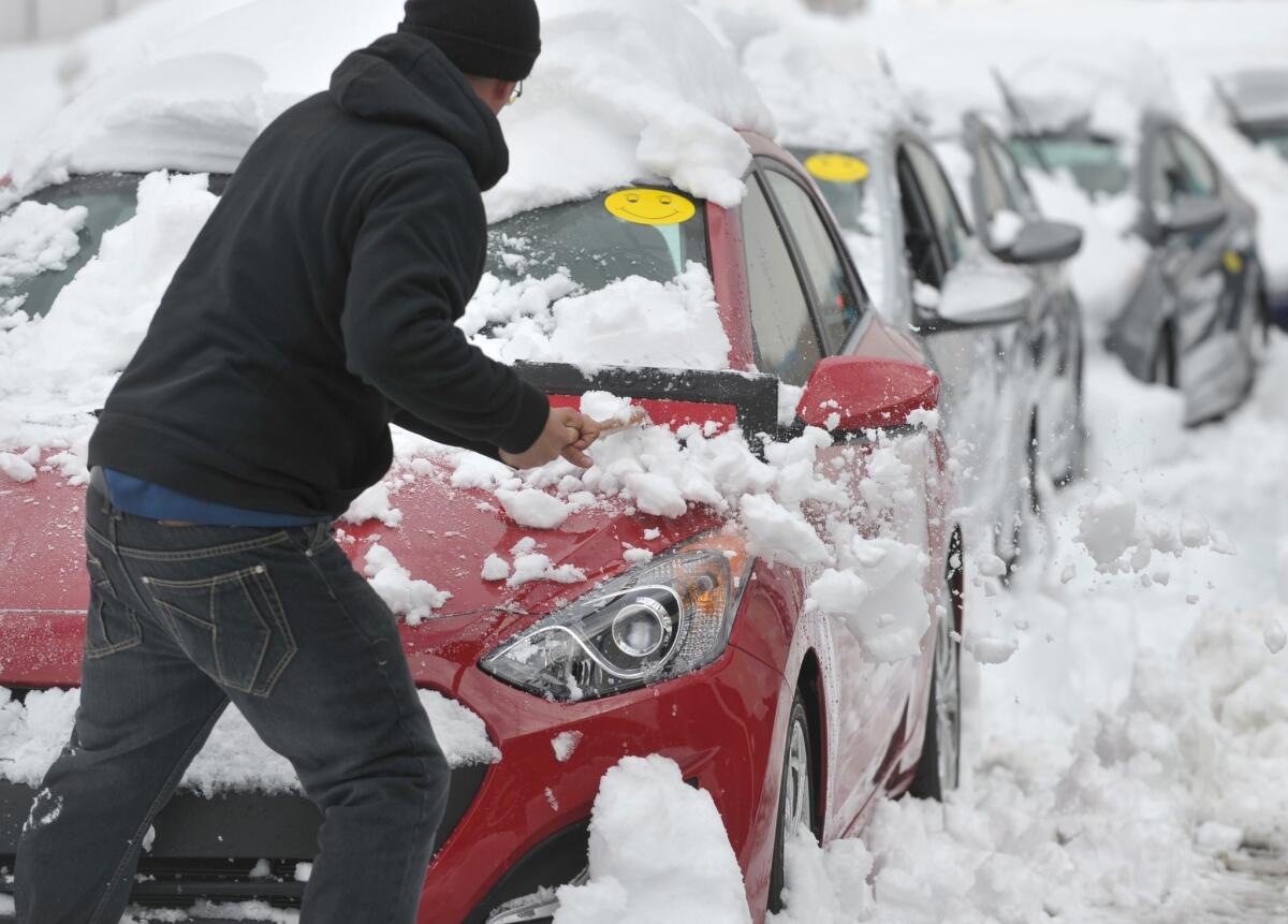 A worker at a New Jersey dealership digs out cars the day after a winter storm in Greenwich Township.