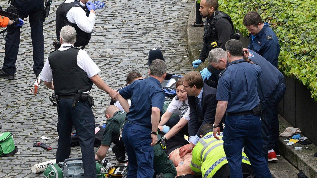 Conservative Member of Parliament Tobias Ellwood, center, helps emergency services attend to an injured person outside the Houses of Parliament in London. (Stefan Rousseau / Associated Press)
