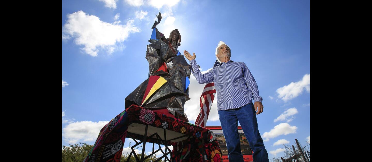 Artist Jim Bliesner stands next to a model of his sculpture, made of stainless steel, of the Virgin Mary as the Statue of Liberty, titled "Welcome the Stranger", that will be 40 feet tall and face the border from Our Lady of Mt. Carmel Catholic Church during a ceremony for the statue at Our Lady of Mt. Carmel Catholic Church in San Ysidro.