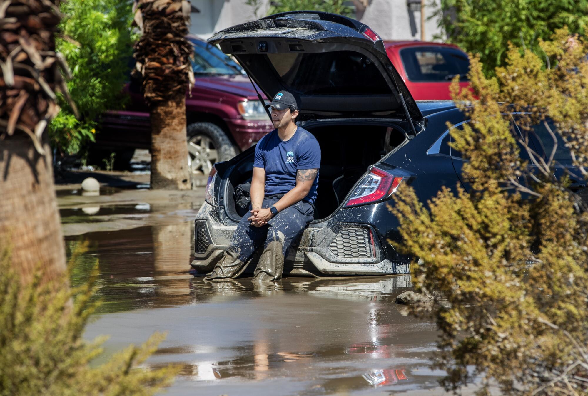 A man waits for help in the back of his stuck car on the flooded Avenida La Vista in Cathedral City, California. 
