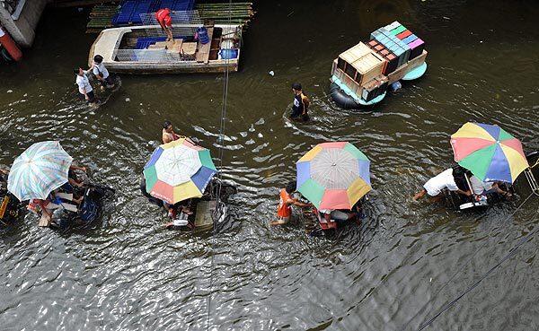 Tricycle drivers transport passengers along a flooded street in the town of Santa Cruz, south of Manila, after Typhoon Parma hit.
