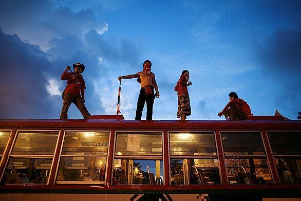 In Bangkok, Thailand, at least two people were killed today amid escalating political unrest. Supporters of former Prime Minister Thaksin Shinawatra stand on a bus in the early-morning hours outside Government House. Red-shirted demonstrators clashed with the army and regular citizens in street battles across the capital. Related story: Thailand violence claims two lives