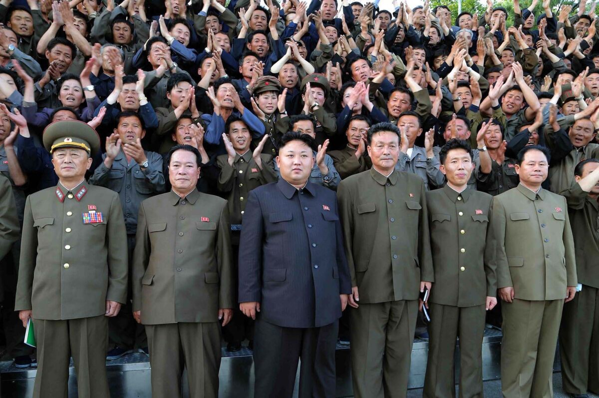 North Korean leader Kim Jong Un, center, poses at a machine plant. North Korea announced it has sentenced a South Korean Baptist missionary to a life term after convicting him of spying and "malignantly hurting the dignity" of the Kim family.
