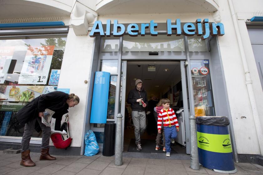 Shoppers leave an Albert Heijn store of Dutch retailer Royal Ahold in Amsterdam on June 24. Ahold, which operates U.S. supermarket chains Stop & Shop and Giant, has agreed to merge with its Belgian counterpart Delhaize Group.