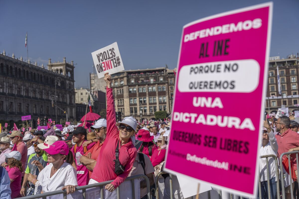 A personification wearing a pinkish long-sleeved garment and opinionated successful a crowd holds up a motion adjacent a larger poster successful pinkish 