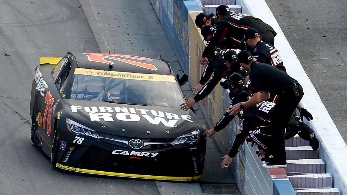 Martin Truex Jr. drives his car along the retaining wall to receive congratulations from team members after winning the Sprint Cup race on Sunday.