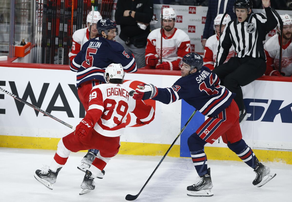 Winnipeg Jets' Brenden Dillon (5) and Detroit Red Wings' Sam Gagner (89) collide as Jets' Zach Sanford (13) reaches for the puck during the second period of an NHL hockey game Wednesday, April 6, 2022, in Winnipeg, Manitoba. (John Woods/The Canadian Press via AP)