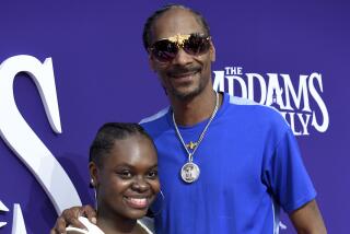 Snoop Dogg, right, wears a blue shirt and blue leather pants and Cori Broadus, left, wears a white blouse and blue jeans