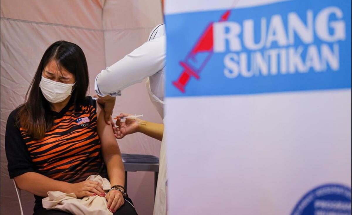 A healthcare worker administers a dose of the Pfizer-BioNTech COVID-19 vaccine to a Malaysian badminton player
