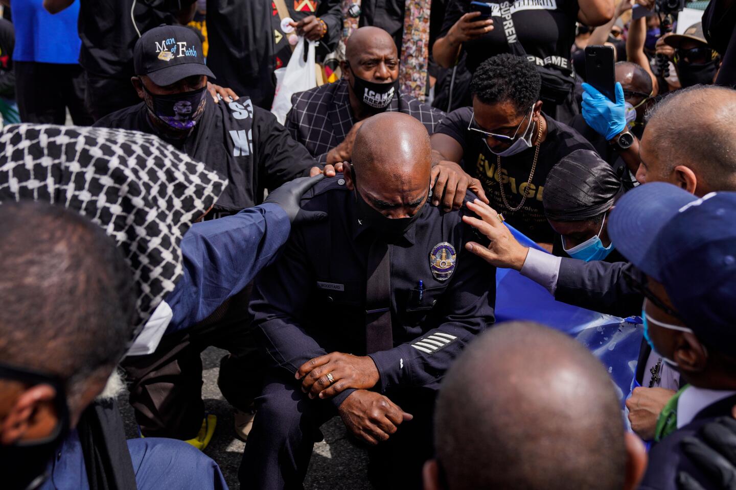 LAPD Cmdr. Gerald Woodyard takes a knee with clergy members from the Los Angeles area