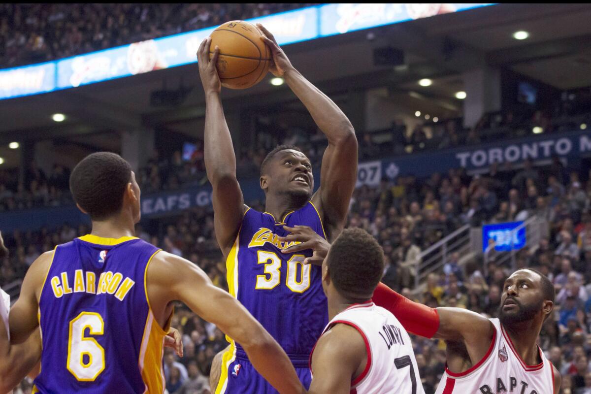 Lakers forward Julius Randle (30) shoots over Raptors defenders Patrick Patterson, right, and Kyle Lowry (7) during the second half.