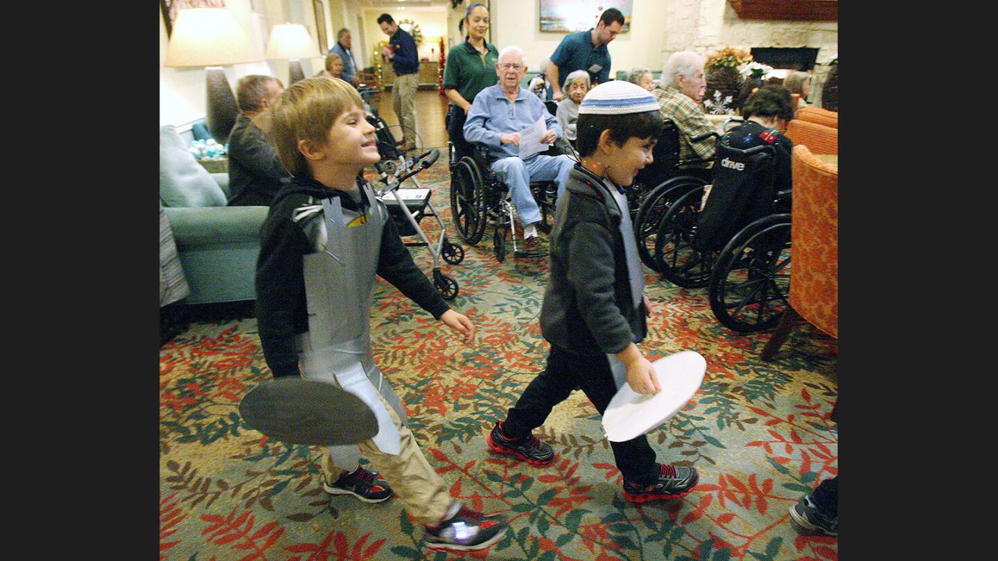 Children from Chabad Burbank Preschool walk in a line as they enter Belmont Village Retirement Home in Burbank to sing holiday songs on Monday, Dec. 19, 2016.