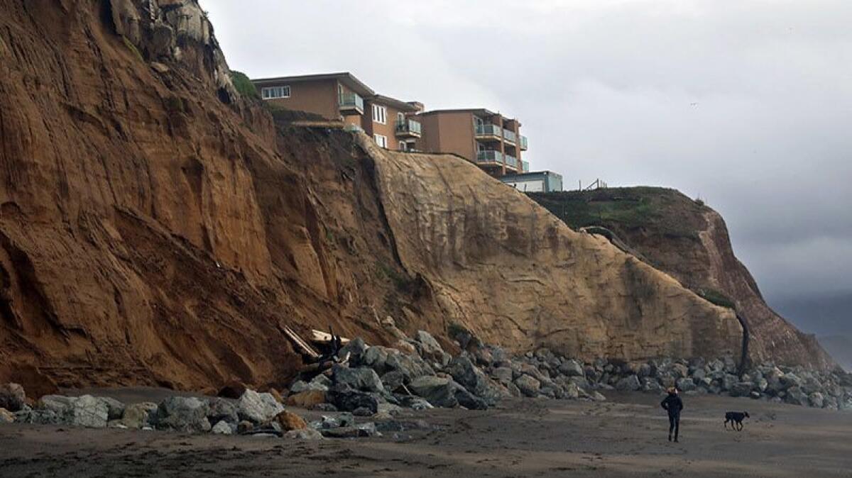 Remnants of a blufftop apartment building in Pacifica fell down to the beach, where large rocks form a barrier against the rising sea.